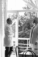 A black-and-white photo of two doctors chatting after a surgery near an open window. Colleagues. Medicine and health.