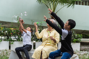 Grandmother and grandchildren playing with soap bubbles outdoors