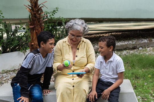 Grandmother playing with tennis ball and tablet with grandsons