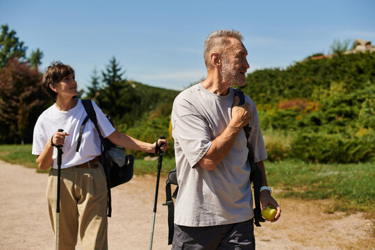 A senior couple hikes on a sunny day, embracing nature and adventure together