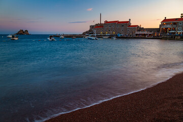 Obraz premium City beach and sea at sunset, panorama of the resort town with embankment and old architecture and street lights