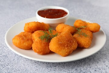 Tasty chicken nuggets with sauce on light grey table, closeup