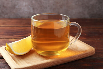 Aromatic tea in cup with lemon on wooden table, closeup