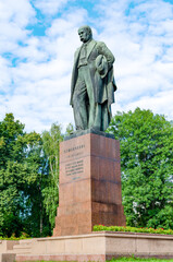Obraz premium Historical statue of Taras Shevchenko in a public park, surrounded by greenery and buildings in the background during the day. Kyiv, Ukraine 02.08.2020