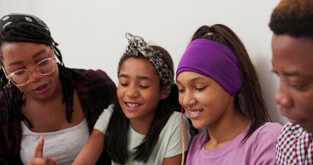 A family sits close together on the floor, with a shot of the married couple and their two daughters faces. They browse the internet, spending time together, discussing, agreeing, and nodding their