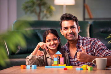 Obraz premium Indian father and daughter building wooden toy tower, spending quality time together
