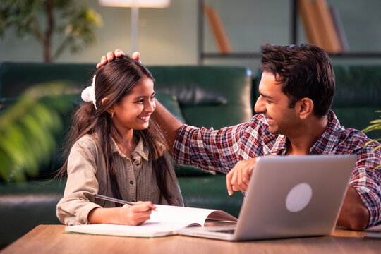 Indian Father helping daughter study on laptop, family learning and bonding at home