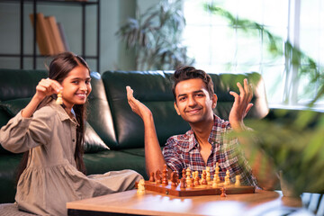 Indian father and daughter playing chess, sharing quality time and fun at home