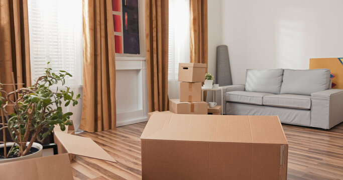 In an empty living room, a single large cardboard box waits to be filled. The move is underway, and the packing begins as the family prepares for their new house.
