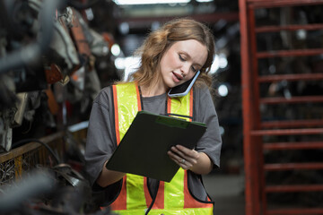 Warehouse auto spare parts. Female warehouse worker working in warehouse auto spare parts, using clipboard check goods management on shelves in workplace