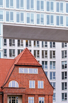 Architectural dialogue between old brick rooflines and sleek glass building in Hamburg, Germany, revealing layers of time and identity within the evolving fabric of the urban landscape