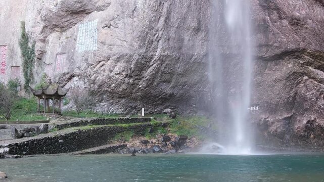 Base of Dalongqiu Waterfall(大龙湫)in Yandang Mountains(雁荡山), Zhejiang China, with traditional pavilion and ancient Chinese stone calligraphy inscriptions carved into the rocky cliff walls