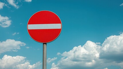A prominent red circular Do Not Enter traffic sign mounted on a grey pole under blue sky with scattered white clouds emp