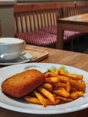 Crispy golden fried food cheese served with French fries and dipping sauce on a wooden table