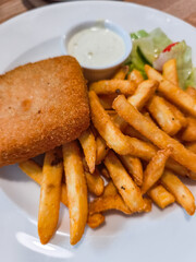 Crispy golden fried cheese served with French fries and creamy dipping sauce on a white plate