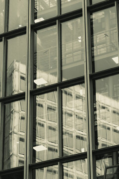 Architectural reflections on glass building revealing inner frameworks and geometric patterns, merging transparency, structure and rhythm in contemporary urban composition
