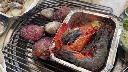 Famous restaurant in Haeundae Beach, Busan, South Korea. Server cooking fresh shellfish (shrimp, scallops, and clams) over a hot charcoal grill.