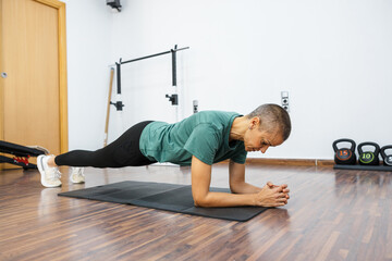 Determined sportswoman performing plank exercise for core strength in gym