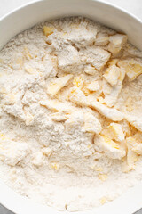 Overhead view of cold butter flour and sugar being mixed to make tart dough in a mixing bowl, process of making tart and pie shell or crust