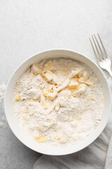 Overhead view of cold butter flour and sugar being mixed to make tart dough in a mixing bowl, process of making tart and pie shell or crust