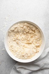 Overhead view of cold butter flour and sugar being mixed to make tart dough in a mixing bowl, process of making tart and pie shell or crust