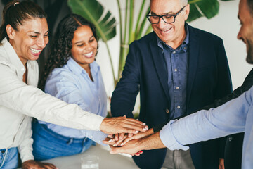 Multiracial business people celebrating together stacking hands inside modern office - Corporate...