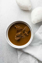 Overhead view of miyan kuka and tuwon on a white plate, top view of northern nigerian miyan kuka soup and rice swallow or tuwon shinkafa
