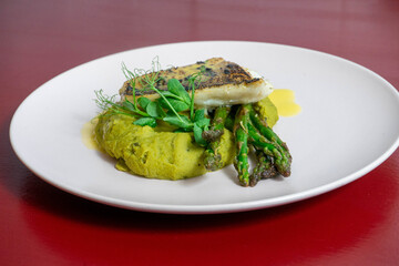 Braised perch fillet served with green asparagus and creamy spinach purée, a healthy and elegant seafood dish perfect for gourmet cuisine.