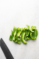 Overhead view of green bell peppers being sliced on a marble countertop, top view of green bell peppers