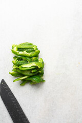 Overhead view of green bell peppers being sliced on a marble countertop, top view of green bell peppers