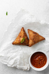 Overhead view of samosa on parchment paper, top view of beef samosa on a white background