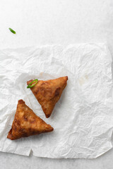 Overhead view of samosa on parchment paper, top view of beef samosa on a white background