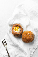 Overhead view of fried scotch eggs on white napkin
