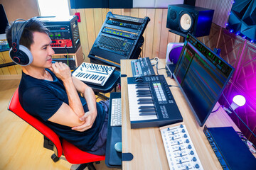 asian male music producer, sound engineer, composer, musician. artist enjoy listening his song in home studio.