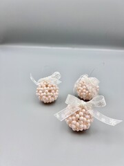 Christmas decorations balls made of large shiny beads with a lace bow in a Scandinavian minimalist style, top view on a light background