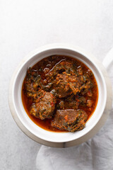 Overhead view of miyan taushe in a white bowl, top view of northern nigerian miyan taushe soup on a white countertop	