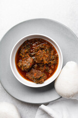 Overhead view of miyan taushe and tuwon on a white plate, top view of northern nigerian miyan taushe soup and rice swallow or tuwon shinkafa