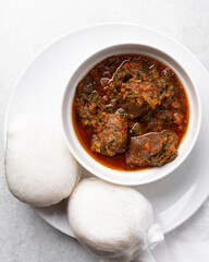 Overhead view of miyan taushe and tuwon on a white plate, top view of northern nigerian miyan taushe soup and rice swallow or tuwon shinkafa