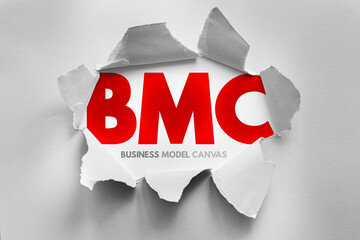 BMC abbreviation for Business Model Canvas revealed behind torn paper. Strategic planning,...