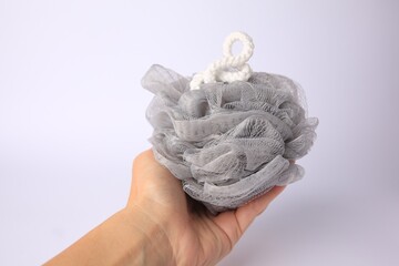 Woman holding grey mesh sponge on white background, closeup