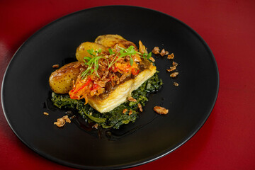 Grilled cod 'à lagareiro' on a bed of Portuguese spinach puree, crafted by a top chef, showcasing traditional flavors and gourmet presentation.
