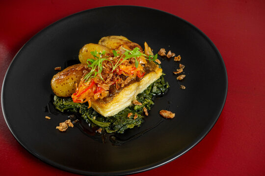 Grilled cod '&agrave; lagareiro' on a bed of Portuguese spinach puree, crafted by a top chef, showcasing traditional flavors and gourmet presentation.