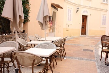 Tables with chairs and umbrellas in stylish outdoor cafe