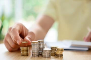 Man counting coins at wooden table indoors, selective focus