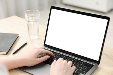 Woman working with laptop at wooden table indoors, closeup. Mockup for design