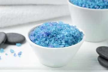 Blue sea salt, spa stones and towel on white wooden table, closeup
