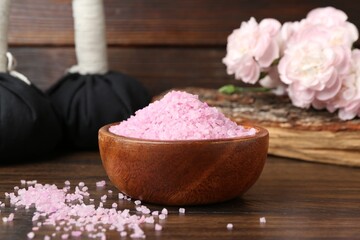 Natural sea salt, flowers and massage sacks on wooden table, closeup