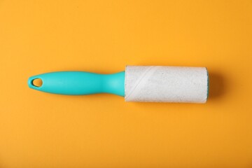 One lint roller on orange background, top view