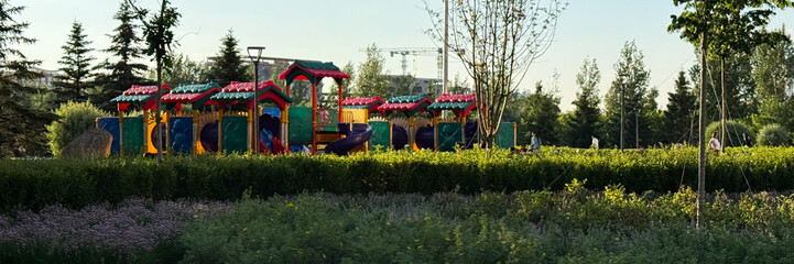 Colorful playground nestled amid lush greenery whispers enchanting tales, evoking Children's Day...