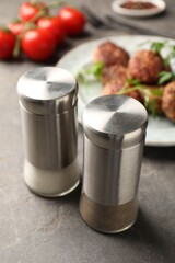Salt and pepper shakers, meatballs on grey table, closeup